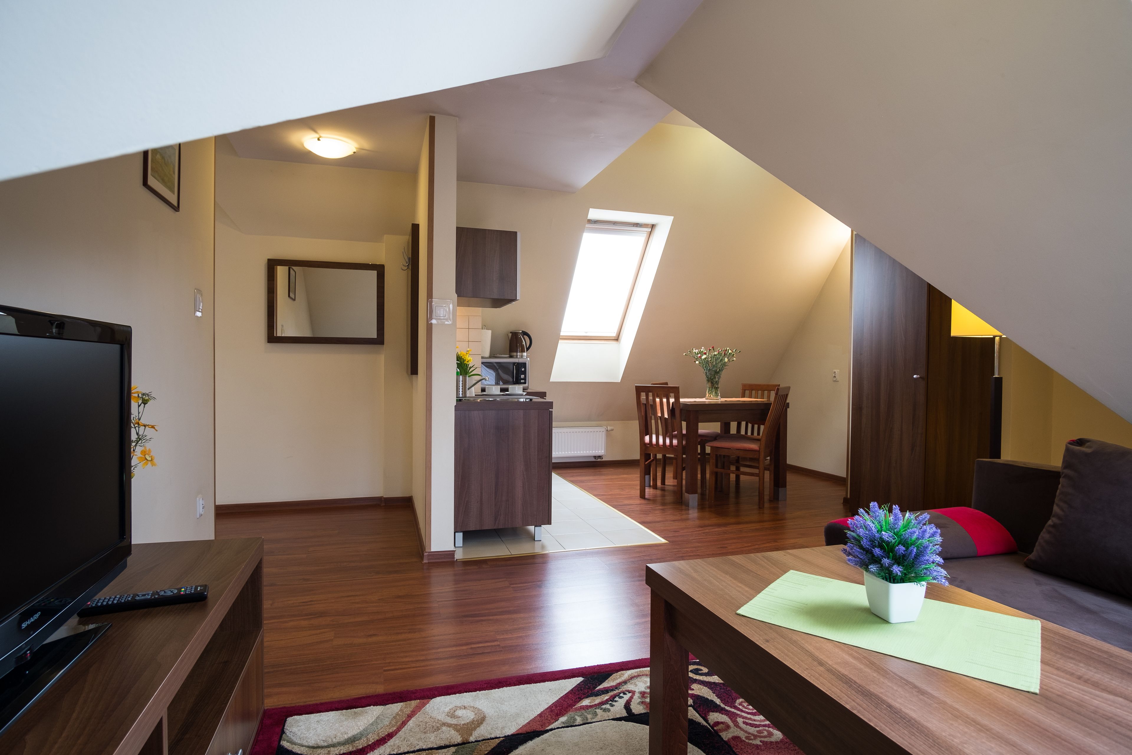 Eine moderne Wohnung mit Essbereich, Küchenzeile und Wohnzimmer mit Fernseher und Sofa.