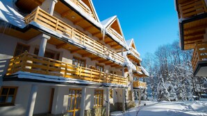 Una cabaña de madera de varios pisos con balcones, rodeada de árboles cubiertos de nieve.