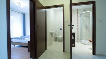 A hotel room with a bed, a bathroom with a shower, and a toilet.