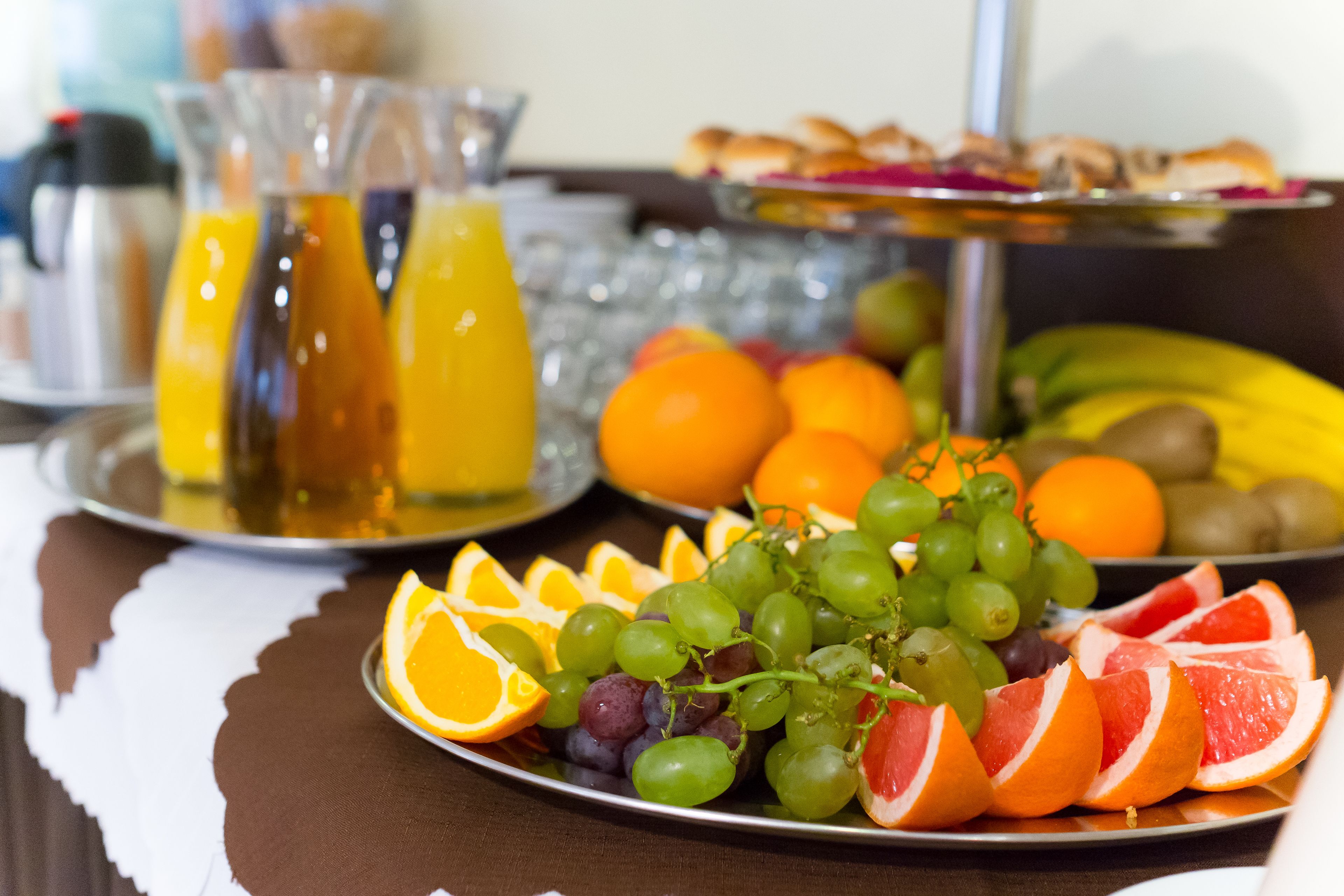 A breakfast buffet with fruits, juices, and pastries.