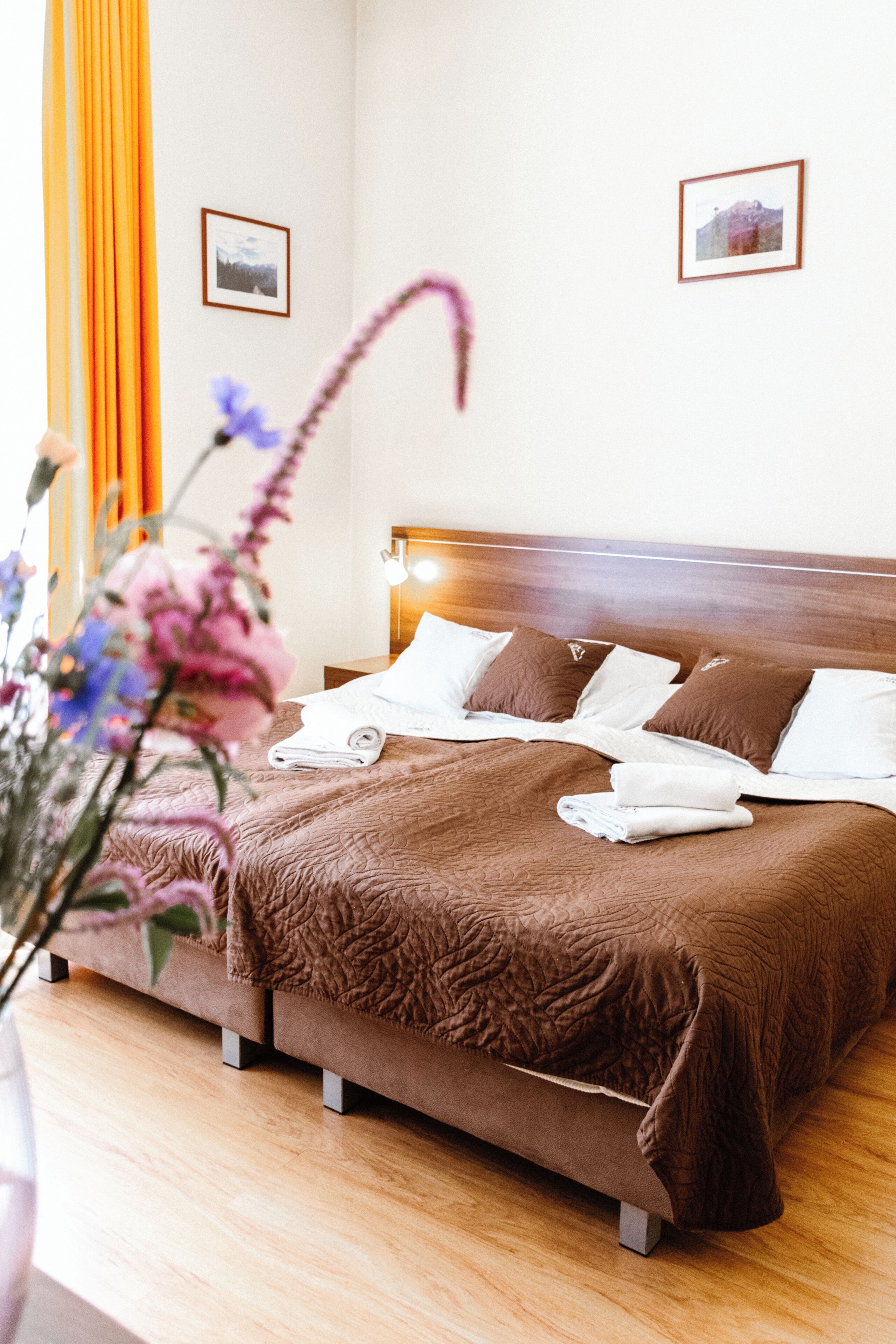 Una cama bien hecha con almohadas y una manta, un cabecero de madera y un cuadro colgado en la pared.