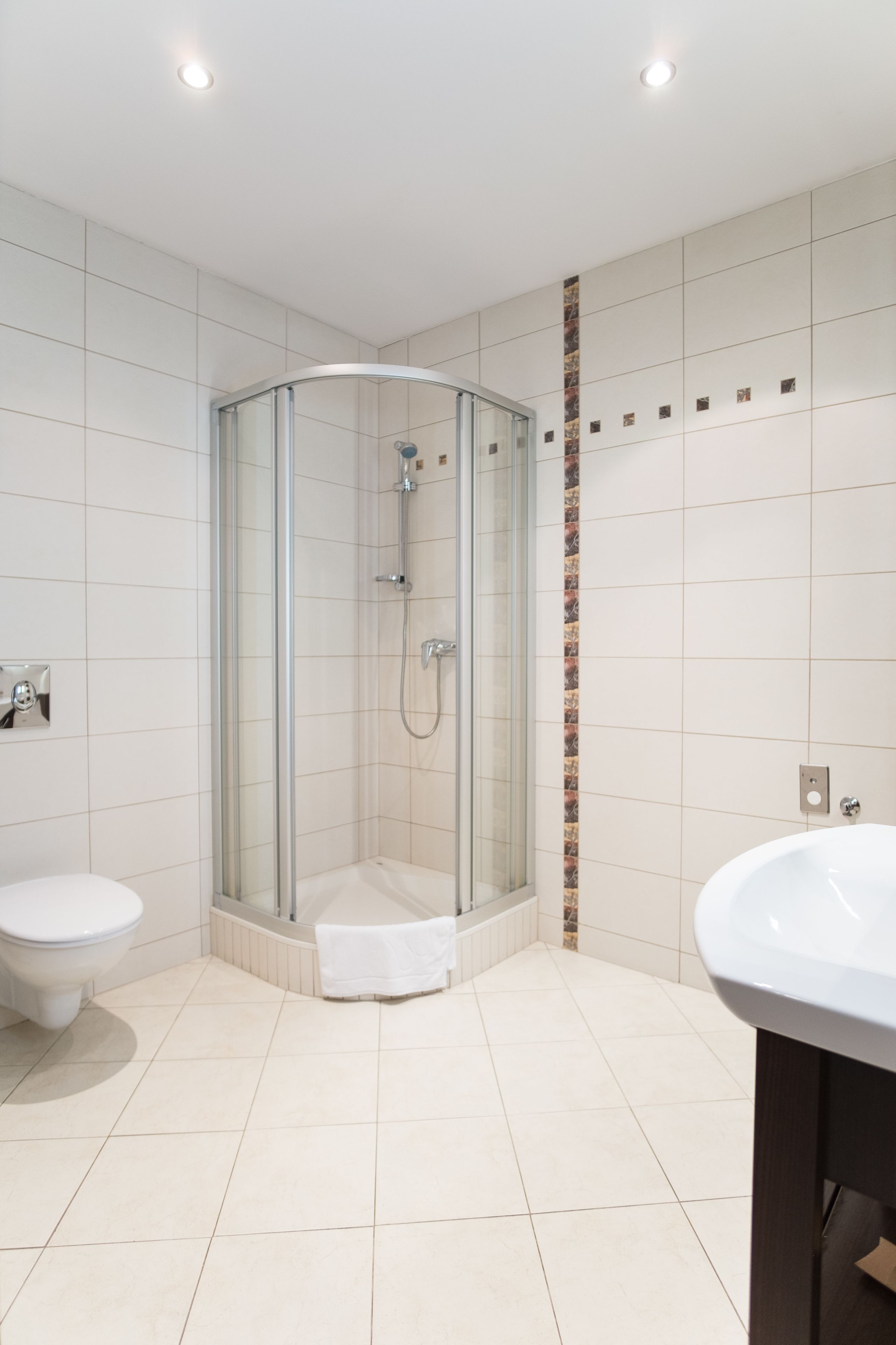 Un baño moderno con ducha de vidrio, dos lavamanos y un inodoro.