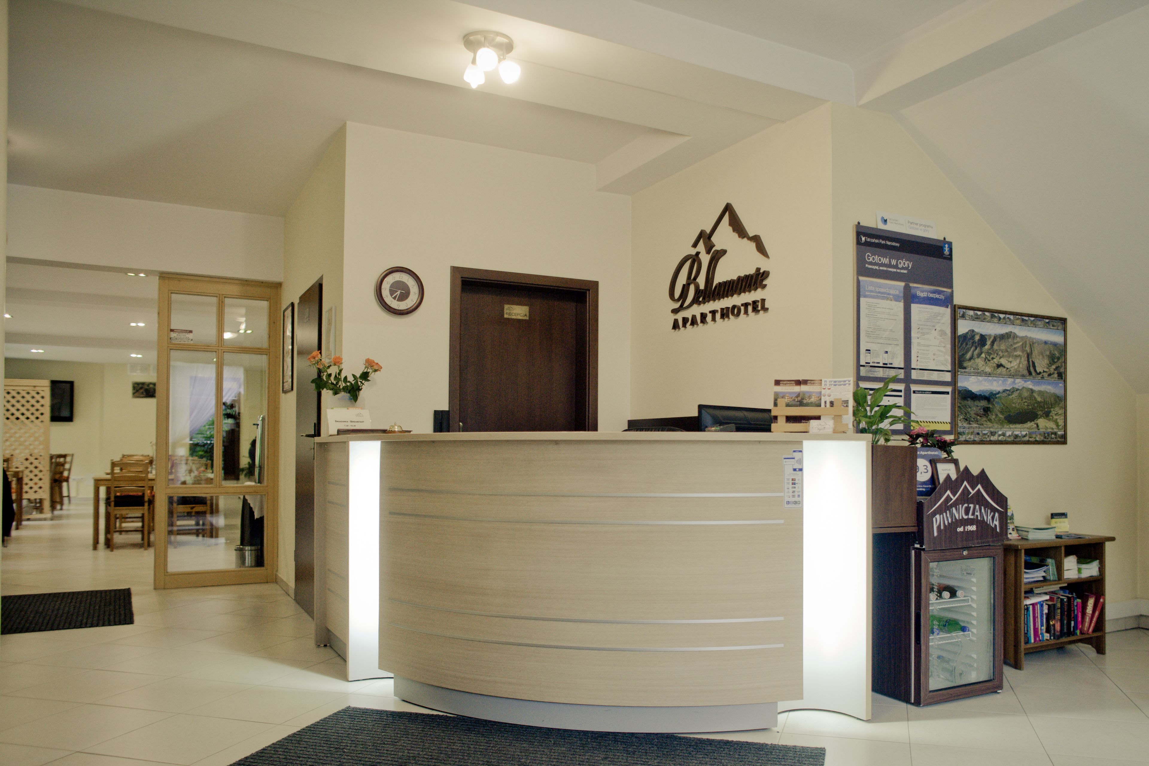 A reception desk with a wooden finish, a clock, and a sign for 'Balmoral Apartments'.