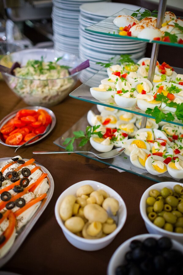 A buffet with various dishes including salads, eggs, and olives.