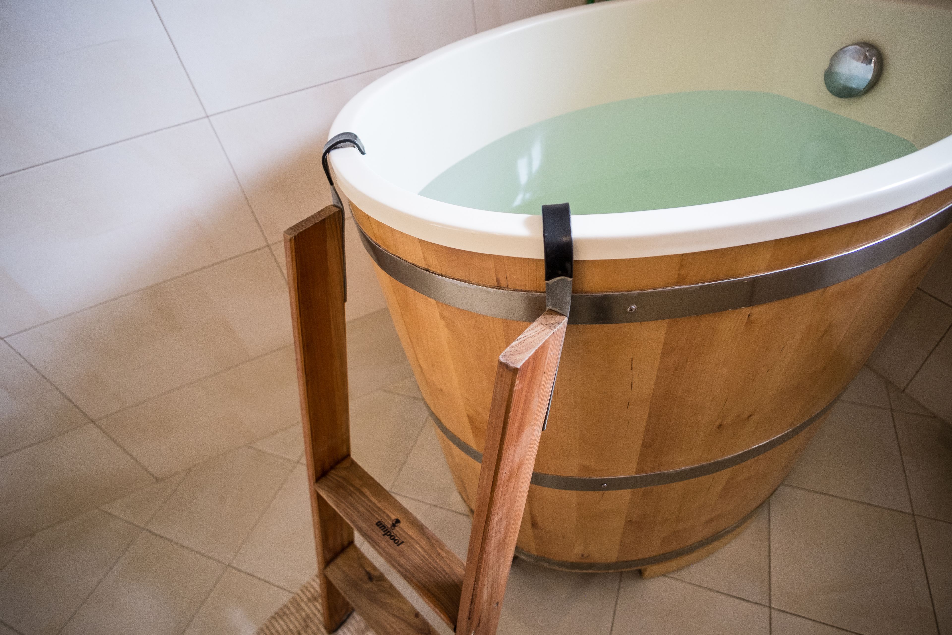 A wooden bathtub with a metal frame and a metal handle.