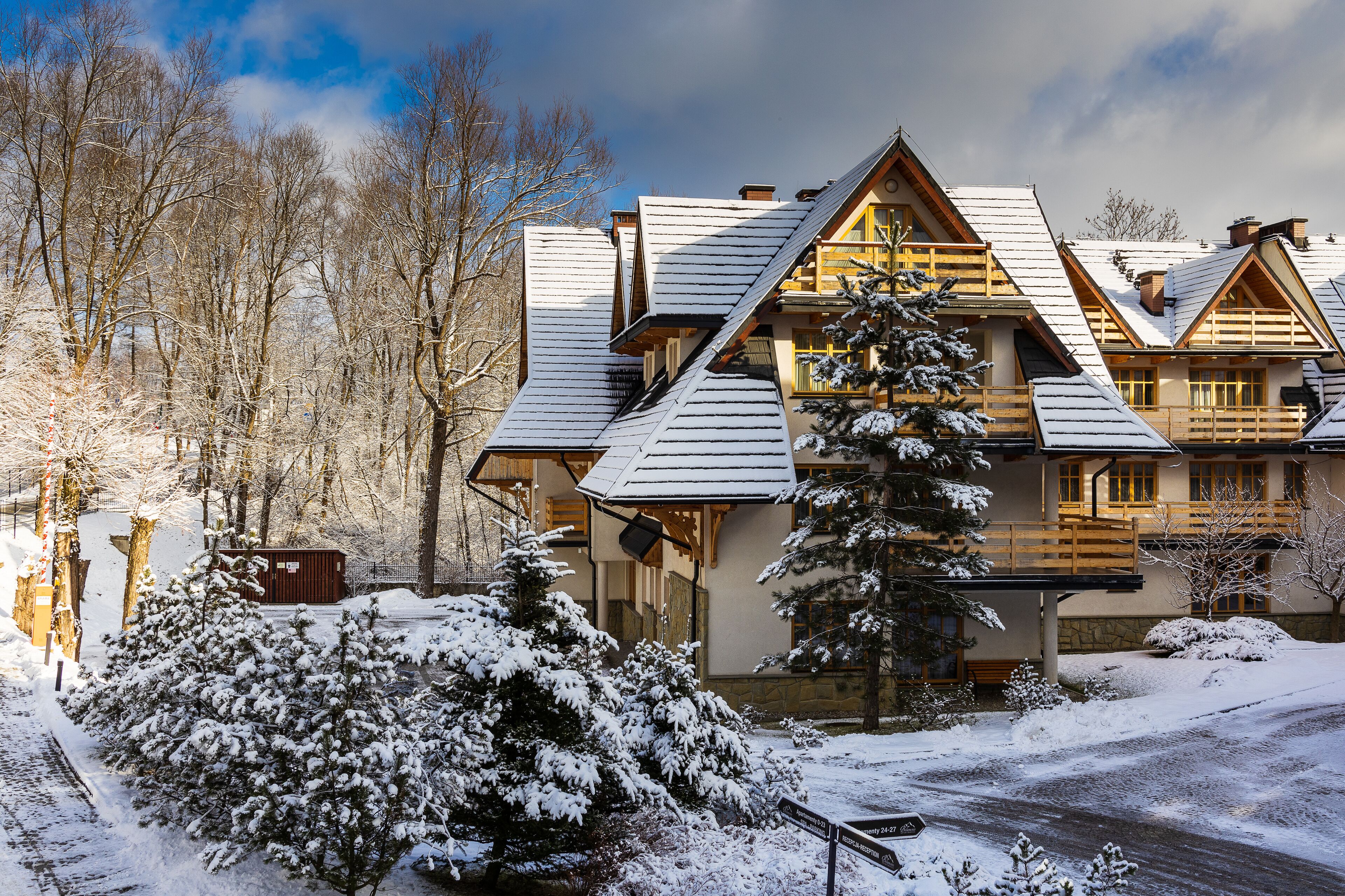 Un bâtiment de style chalet, doté d’un toit à forte pente, de balcons en bois et surplombant un paysage enneigé.