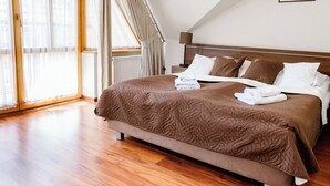Un dormitorio con una cama grande, cabecera de madera, ventana con cortinas y un radiador.