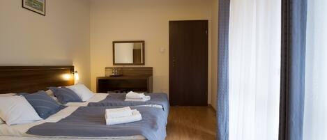 A hotel room with a bed, a bedside table, a mirror, and a door.