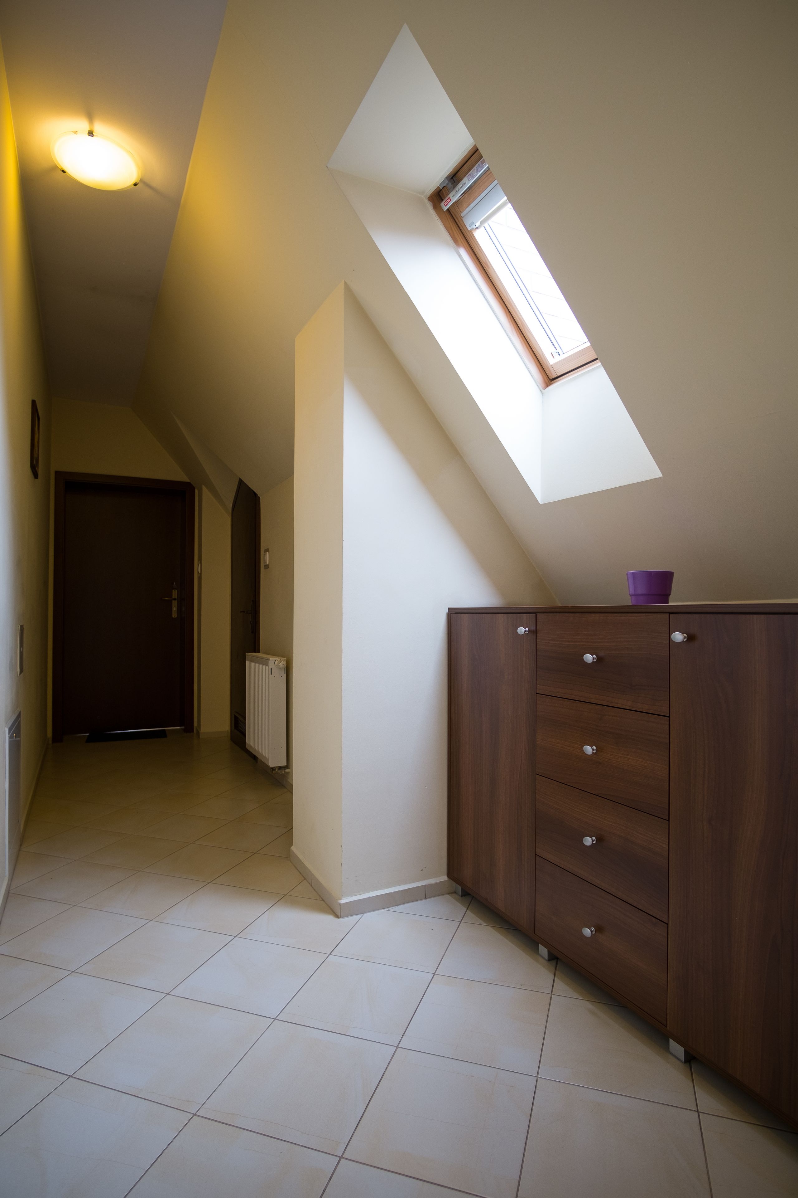 Ein schmaler Flur mit Oberlicht, einem Holzschrank und einer Heizkörper.