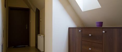 A narrow hallway with a skylight, a wooden cabinet, and a radiator.