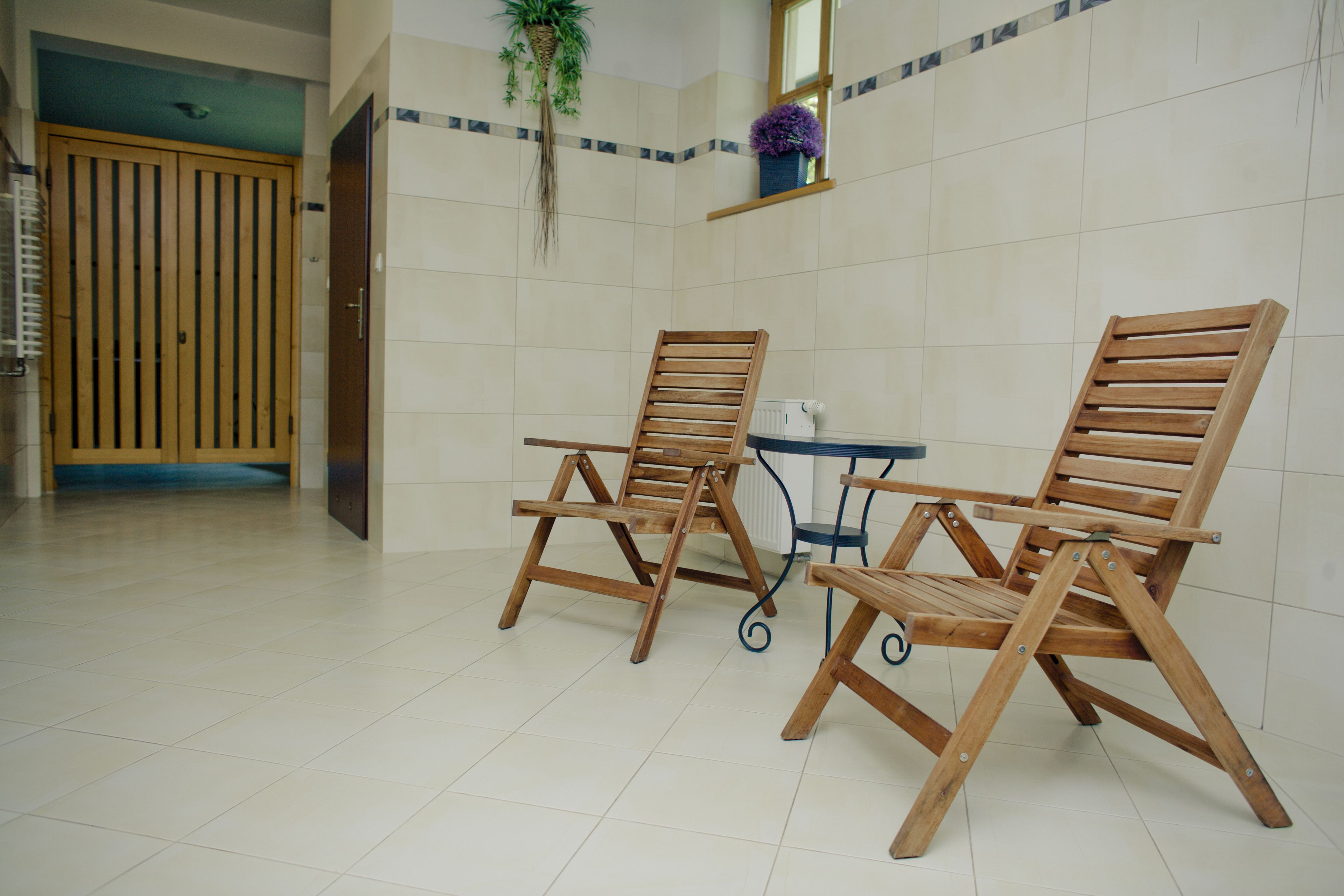 A room with two wooden chairs, a small table, and a potted plant.