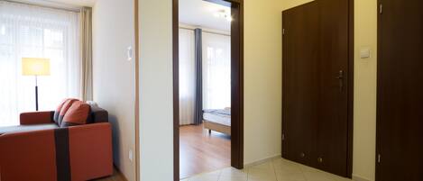 A hotel room with a sofa, a bed, and a wooden floor.