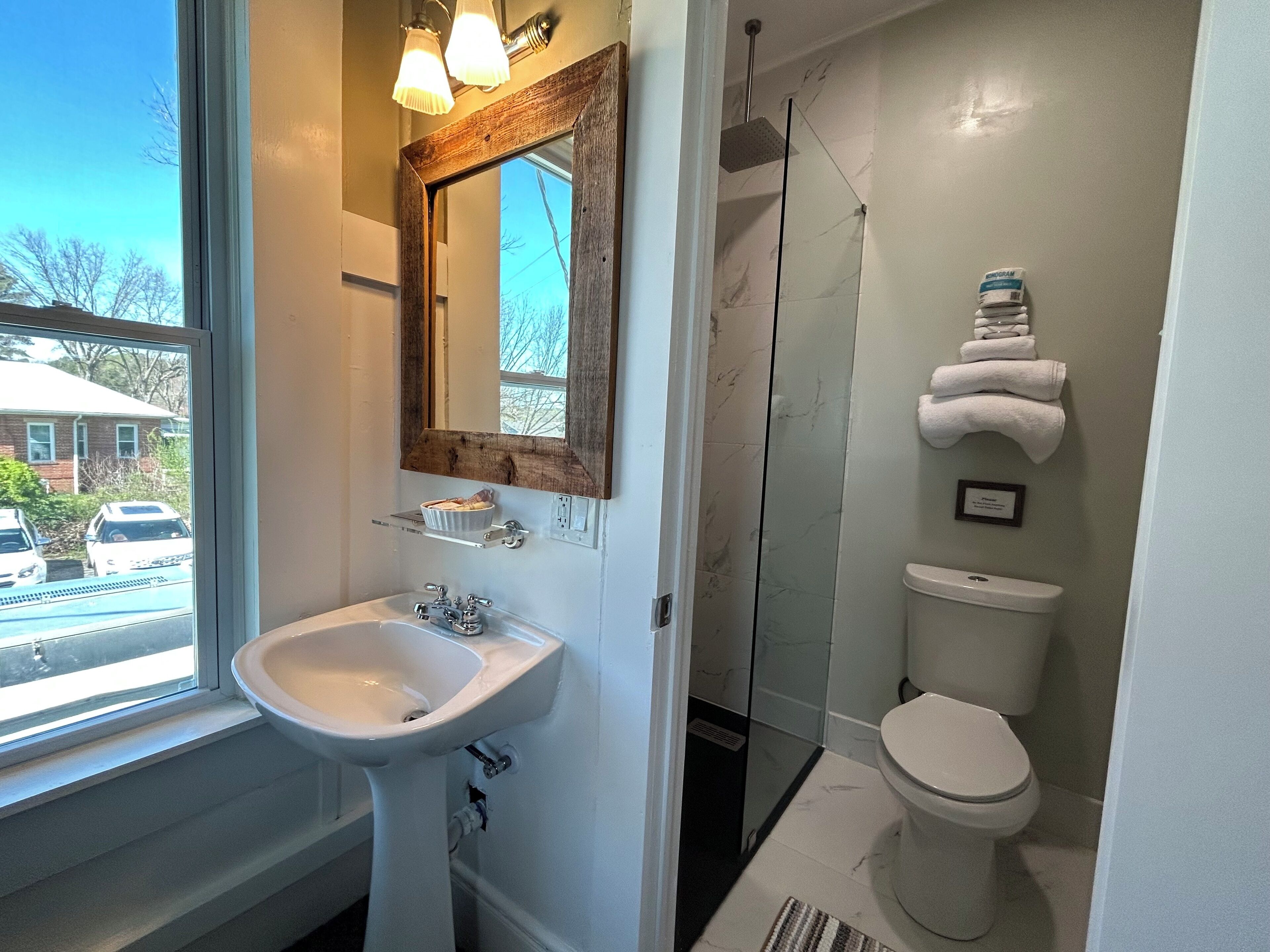 Une salle de bain avec un lavabo blanc, un miroir, des toilettes et une douche.