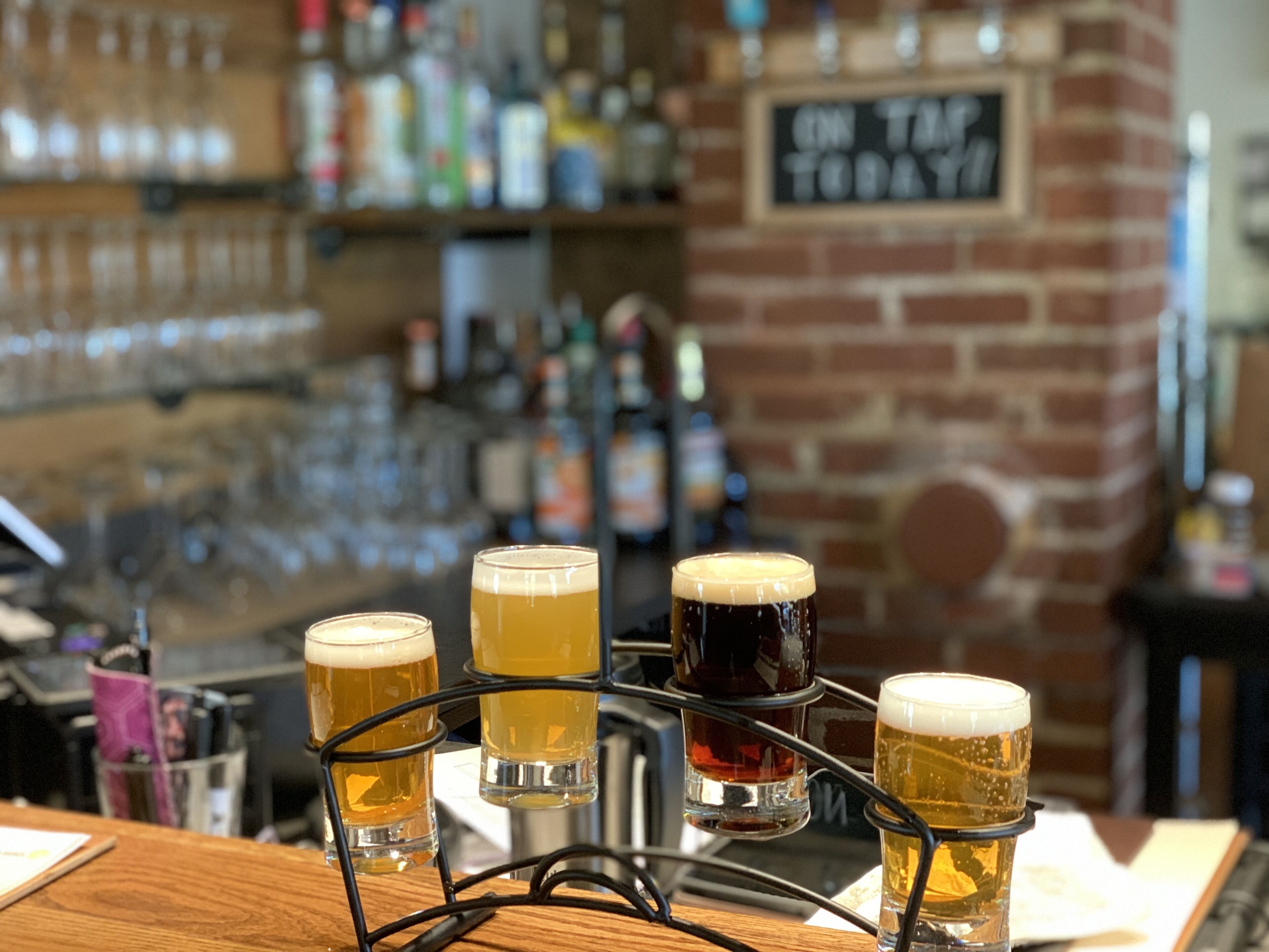 Un bar con una selección de vasos de cerveza en un porta vasos.