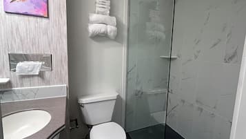 A modern bathroom with a marble sink, toilet, and glass shower enclosure.