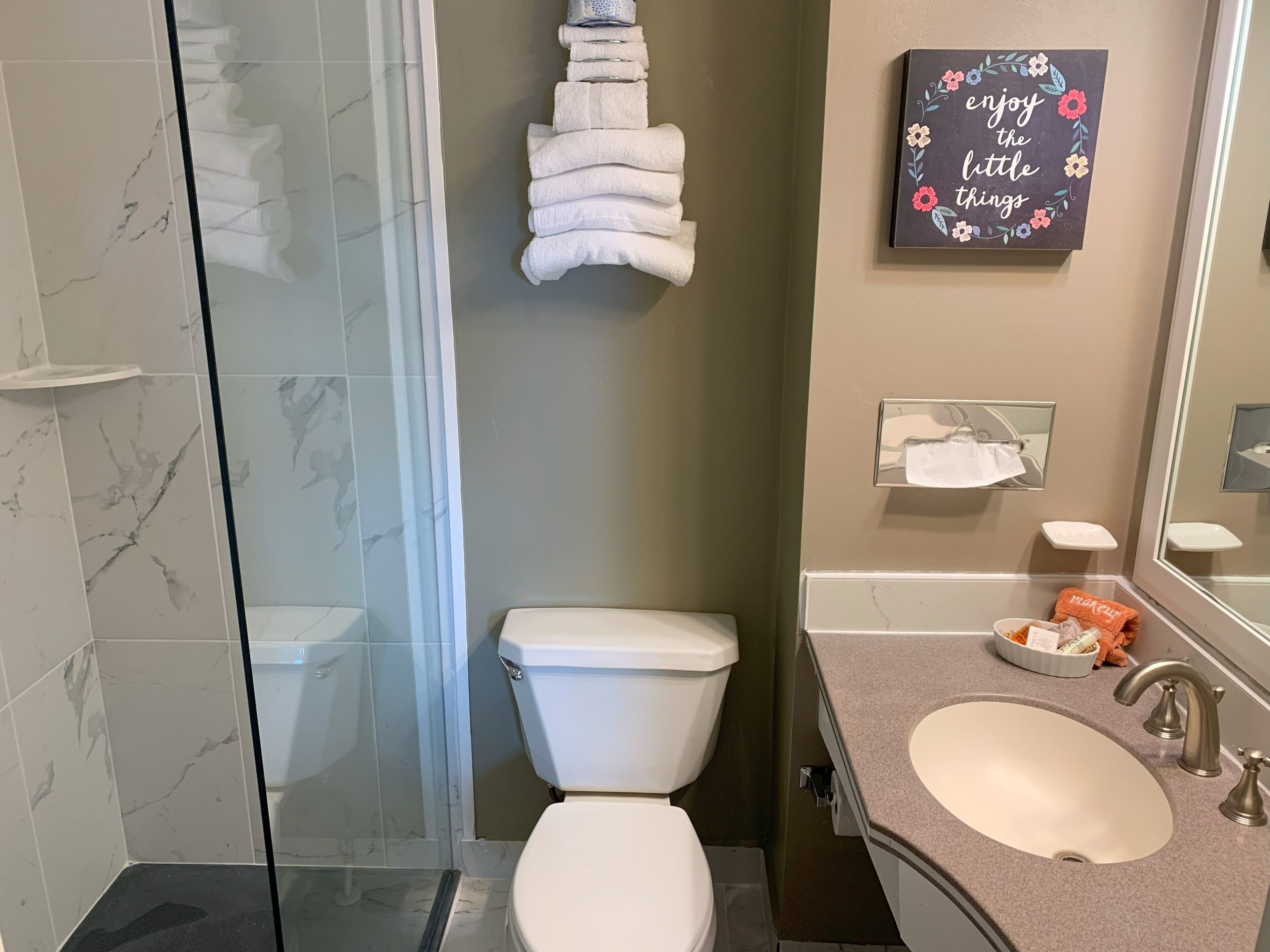 Une salle de bain équipée de toilettes, d’un lavabo et d’une douche à parois de verre.