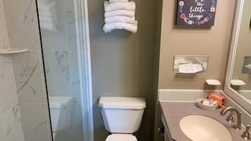 Une salle de bain équipée de toilettes, d’un lavabo et d’une douche à parois de verre.