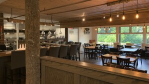 Un restaurante con decoración rústica, que presenta vigas de madera a la vista y un gran tronco de árbol como centro de atención.