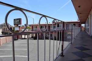 Un motel con un letrero que dice "Capri Motel", un estacionamiento y un corredor cubierto con barandillas.