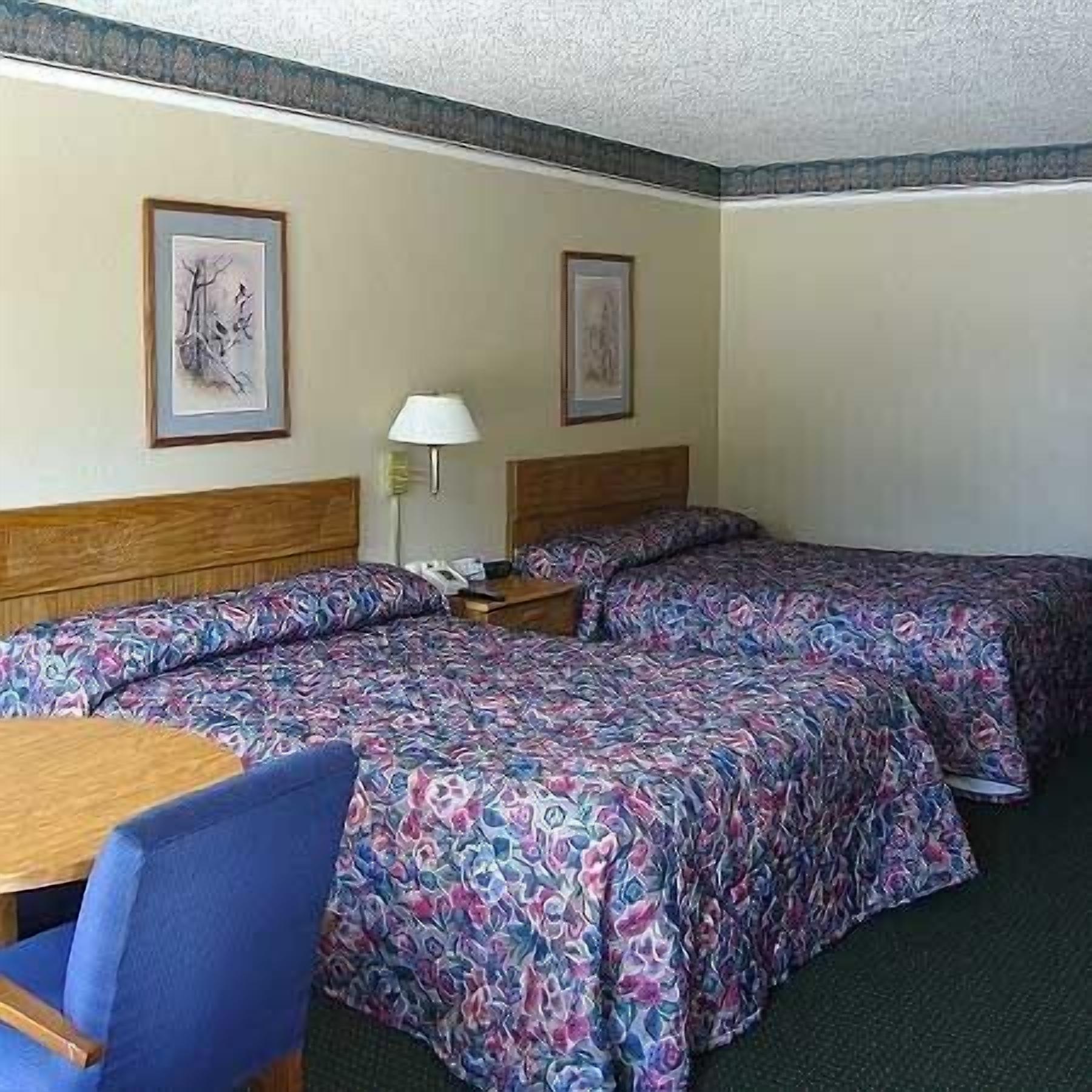 A hotel room with two beds, a desk, and a chair.