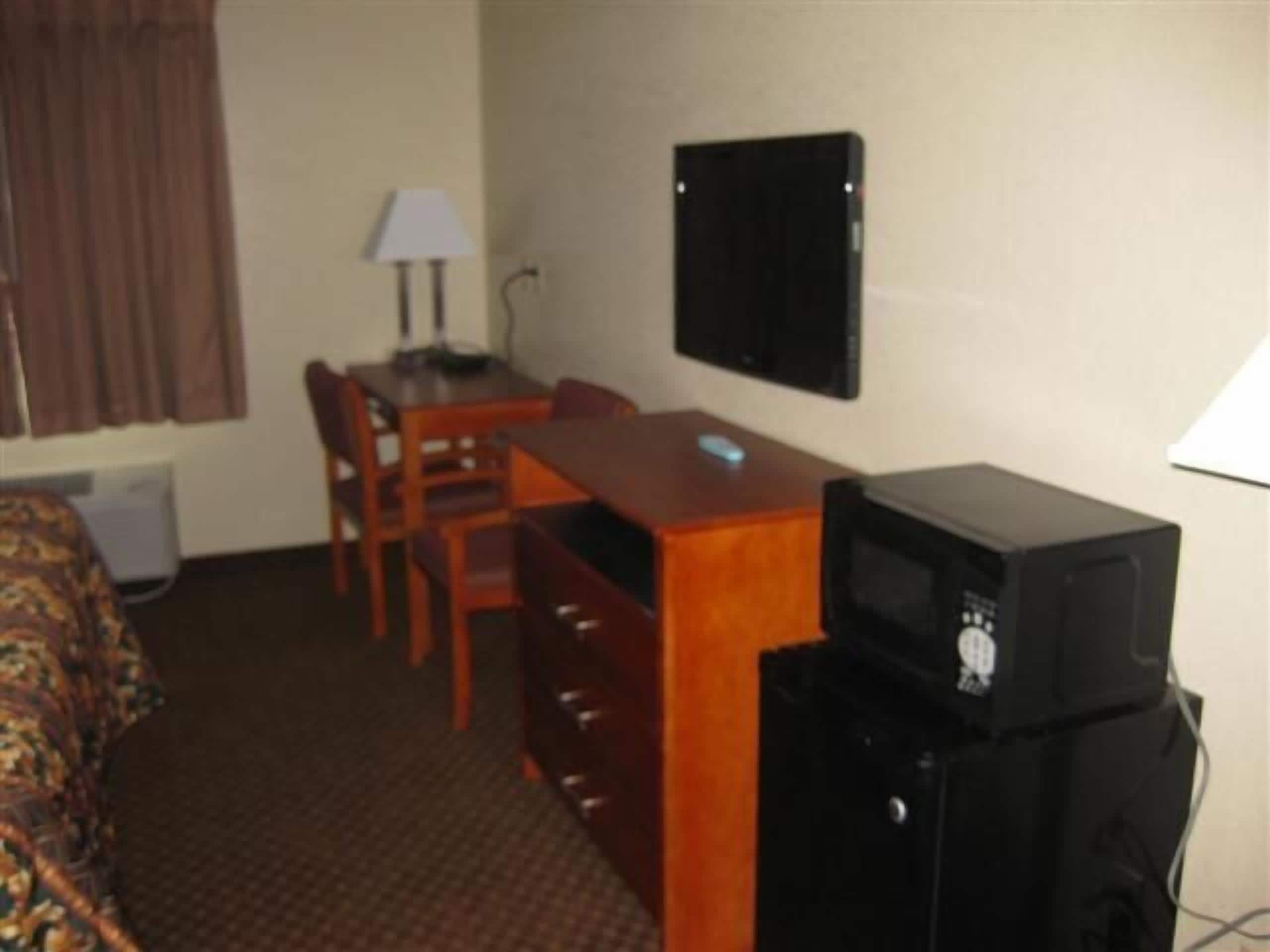 A hotel room with a bed, a desk with a computer, a television, and a chair.