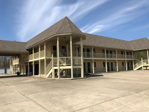 A multi-story motel with a central atrium, balconies, and a covered parking area.