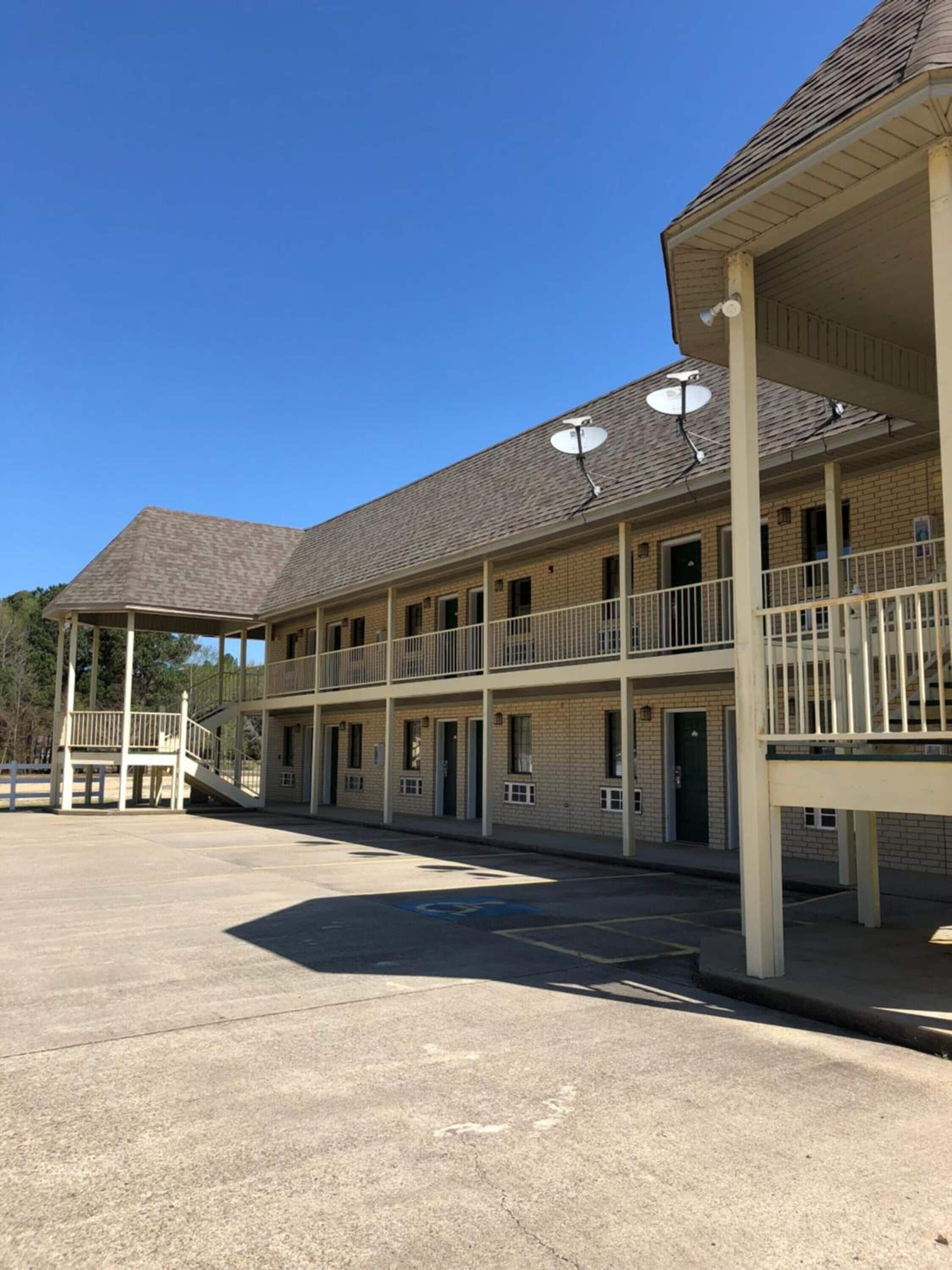 Un motel composé d’un bâtiment à deux étages, d’un espace de stationnement couvert et d’un espace extérieur clôturé.