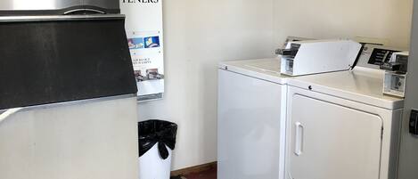 Un cuarto de lavandería con un refrigerador de acero inoxidable, una lavadora y una secadora.