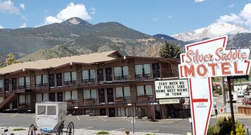 Un motel con un letrero que dice 'Silver Saddle Motel' y un cartel que indica 'Quédate con nosotros, te sentirás como en casa, las mejores vistas del pueblo'.
