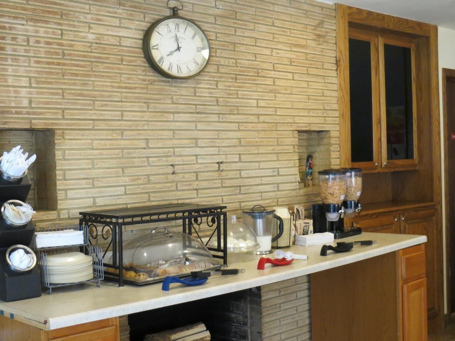 A kitchen with a clock, buffet setup, and wooden cabinets.