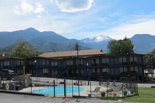 Un hotel de varios pisos con piscina, rodeado de montañas.