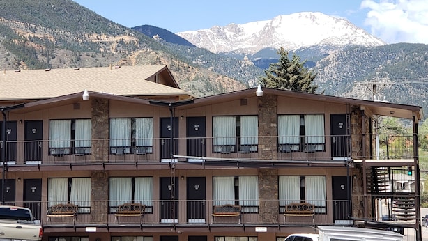A multi-story hotel with balconies, numbered rooms, and a mountainous backdrop.
