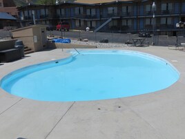 Una piscina de borde curvo, rodeada por una terraza de concreto.