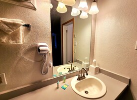 Un baño con lavamanos, espejo, toallero y secador de pelo.