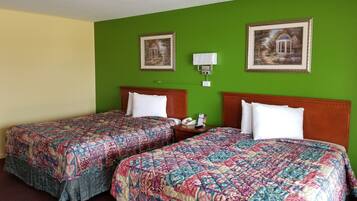 A hotel room with two beds, green walls, and framed pictures on the wall.