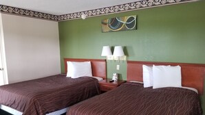 A hotel room with two beds, green walls, and a decorative painting above the beds.