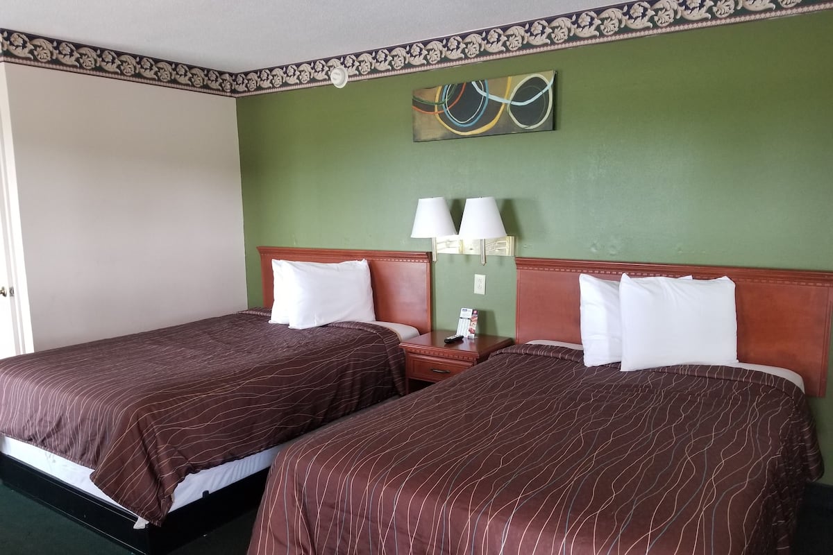 A hotel room with two beds, green walls, and a decorative painting above the beds.