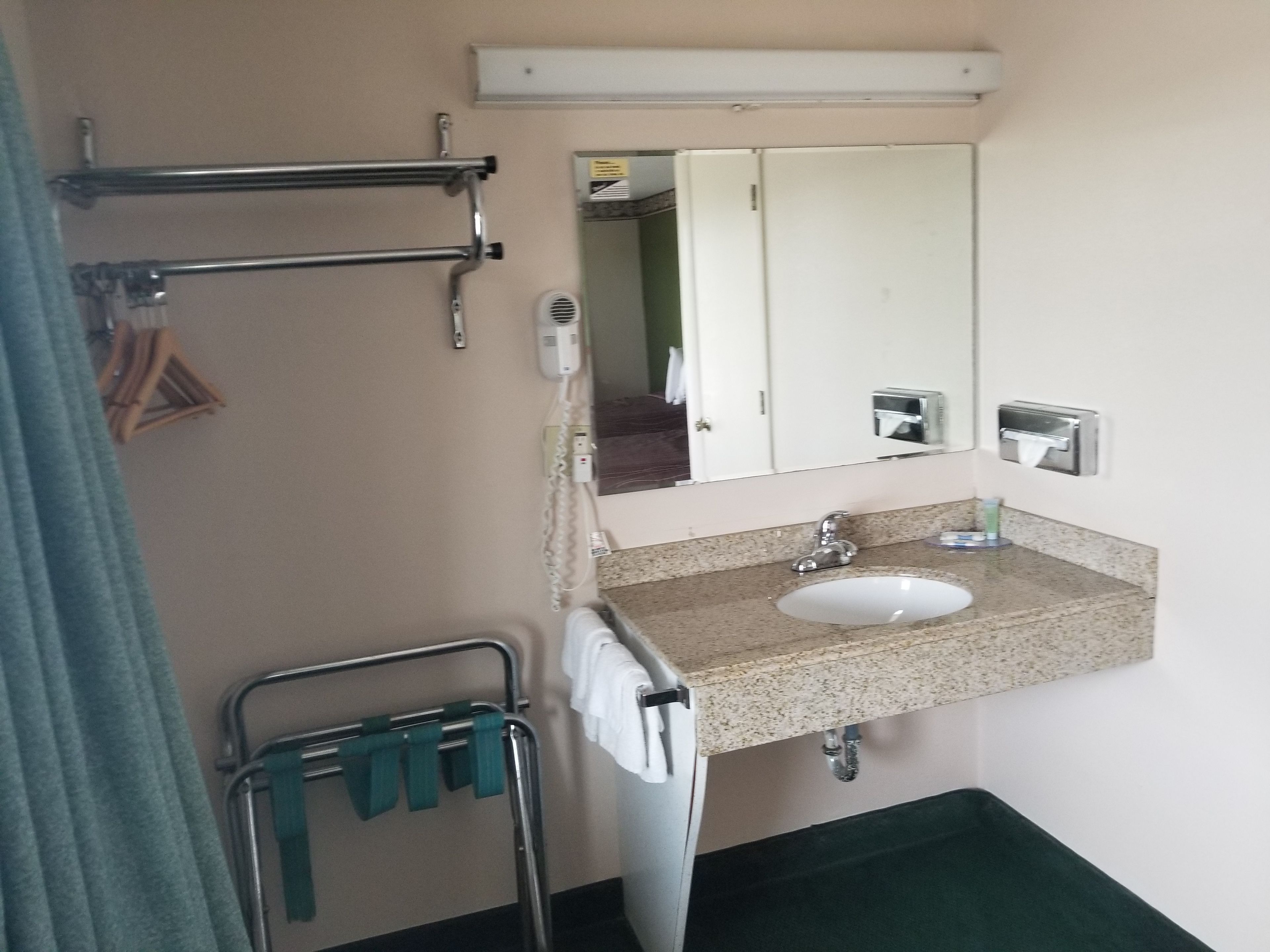 Un baño con lavamanos, espejo, toallero y zona de ducha.