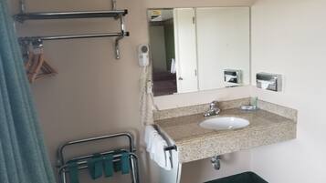 Un baño con lavamanos, espejo, toallero y zona de ducha.
