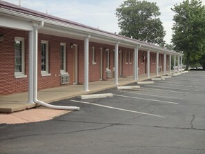 A row of single-story brick buildings with a covered walkway, each with a window and a door.