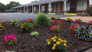 A motel with a brick facade, a covered porch, and a parking lot.