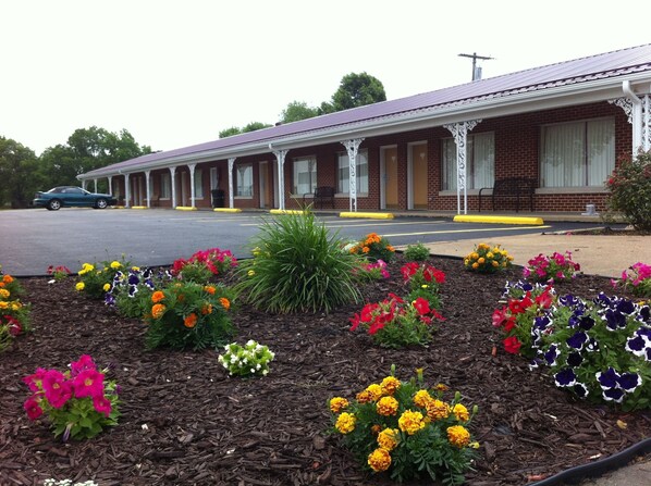A motel with a brick facade, a covered porch, and a parking lot.