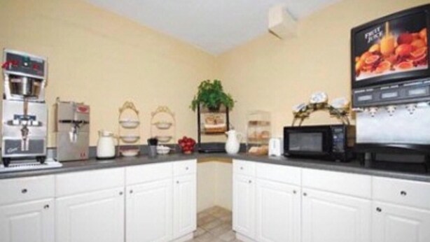 A kitchen with white cabinets, a coffee machine, a microwave, and a fruit juice dispenser. - OYO Hotel Richburg SC I-77 (Richburg)