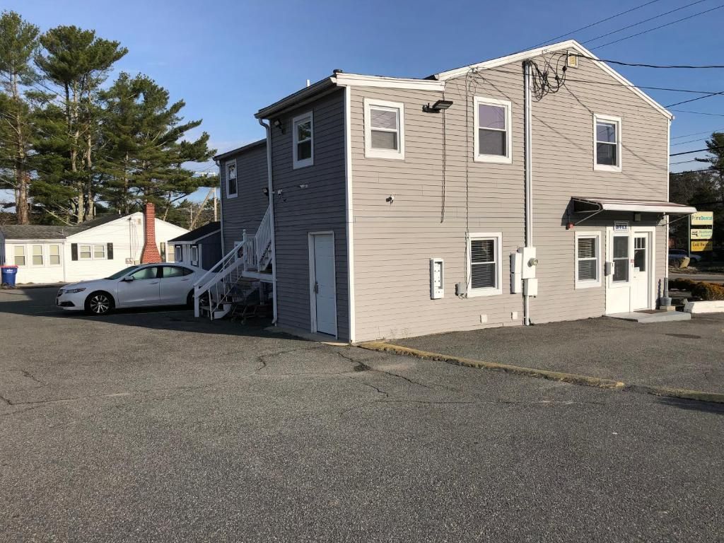 A two-story building with a garage, a staircase, and a small porch.