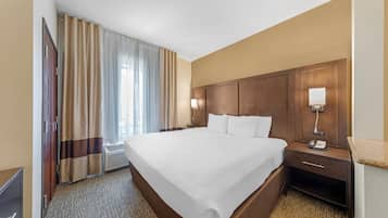 A hotel room with a large bed, a bedside table with a lamp, a wardrobe, and a television.