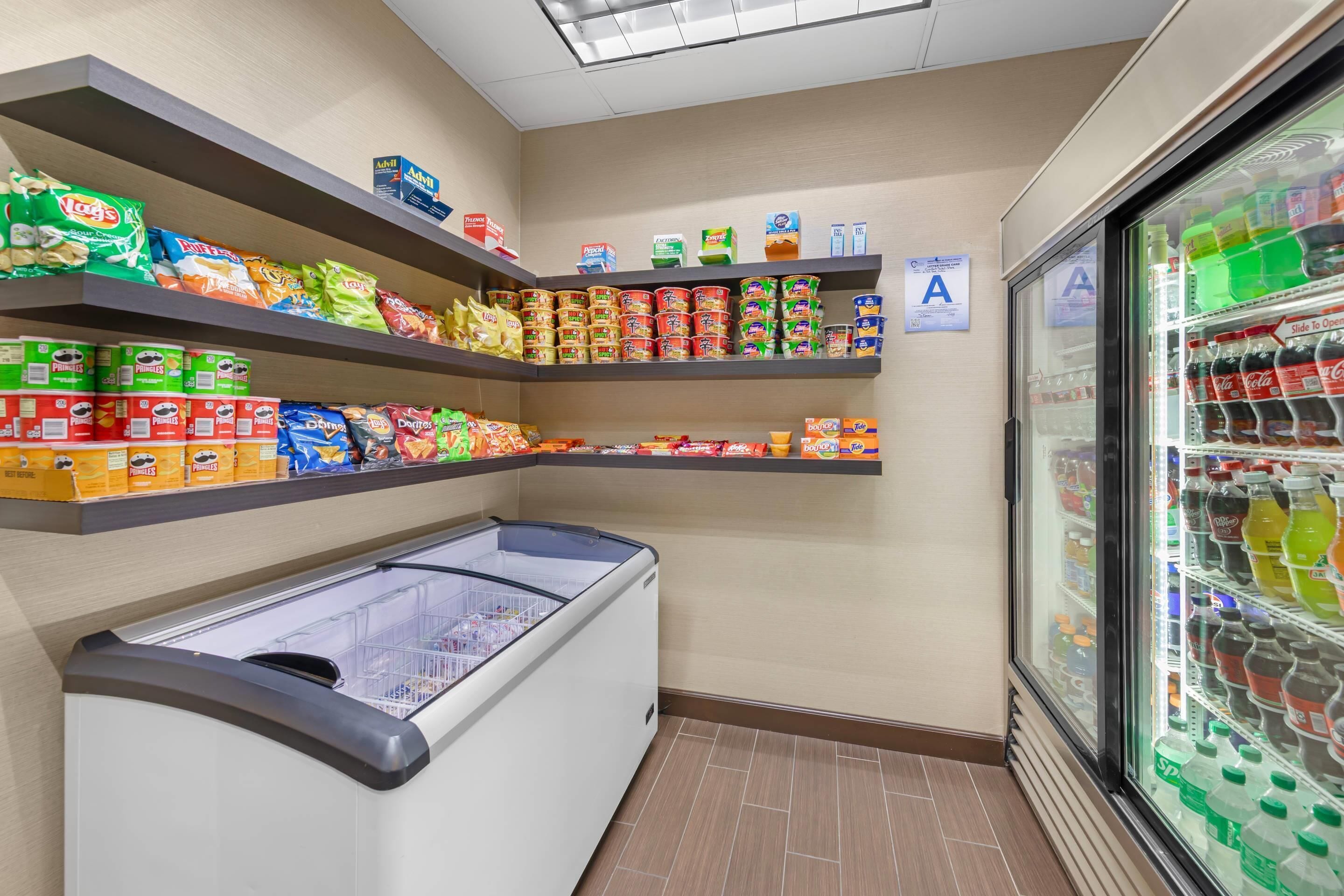 A grocery store interior with shelves stocked with various food items and a refrigerated section with beverages.