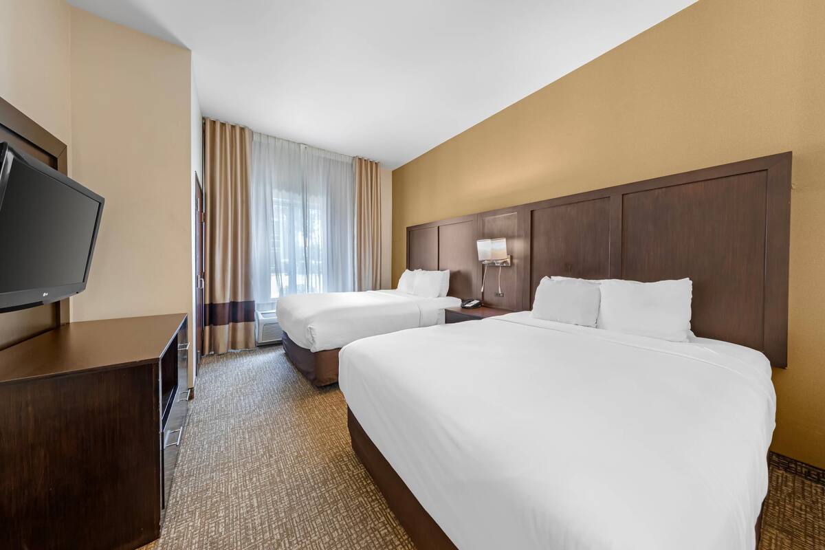 Une chambre d’hôtel avec deux lits, une télévision et un bureau.