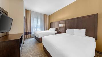 A hotel room with two beds, a TV, and a desk.
