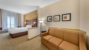 Una habitación de hotel con una cama, un sofá, un escritorio y tres cuadros en la pared.