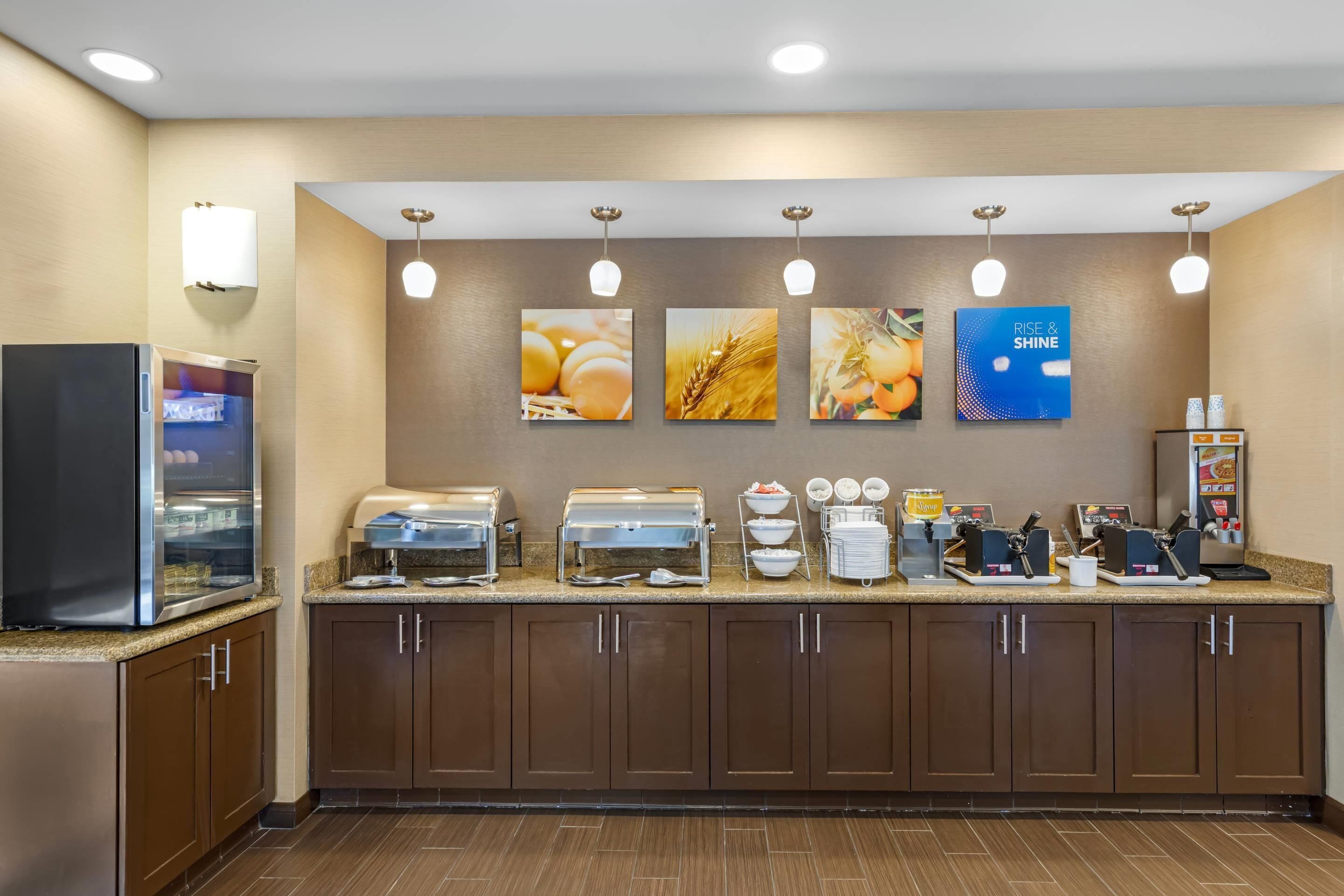 A breakfast bar with a refrigerator, coffee maker, and cereal dispenser.